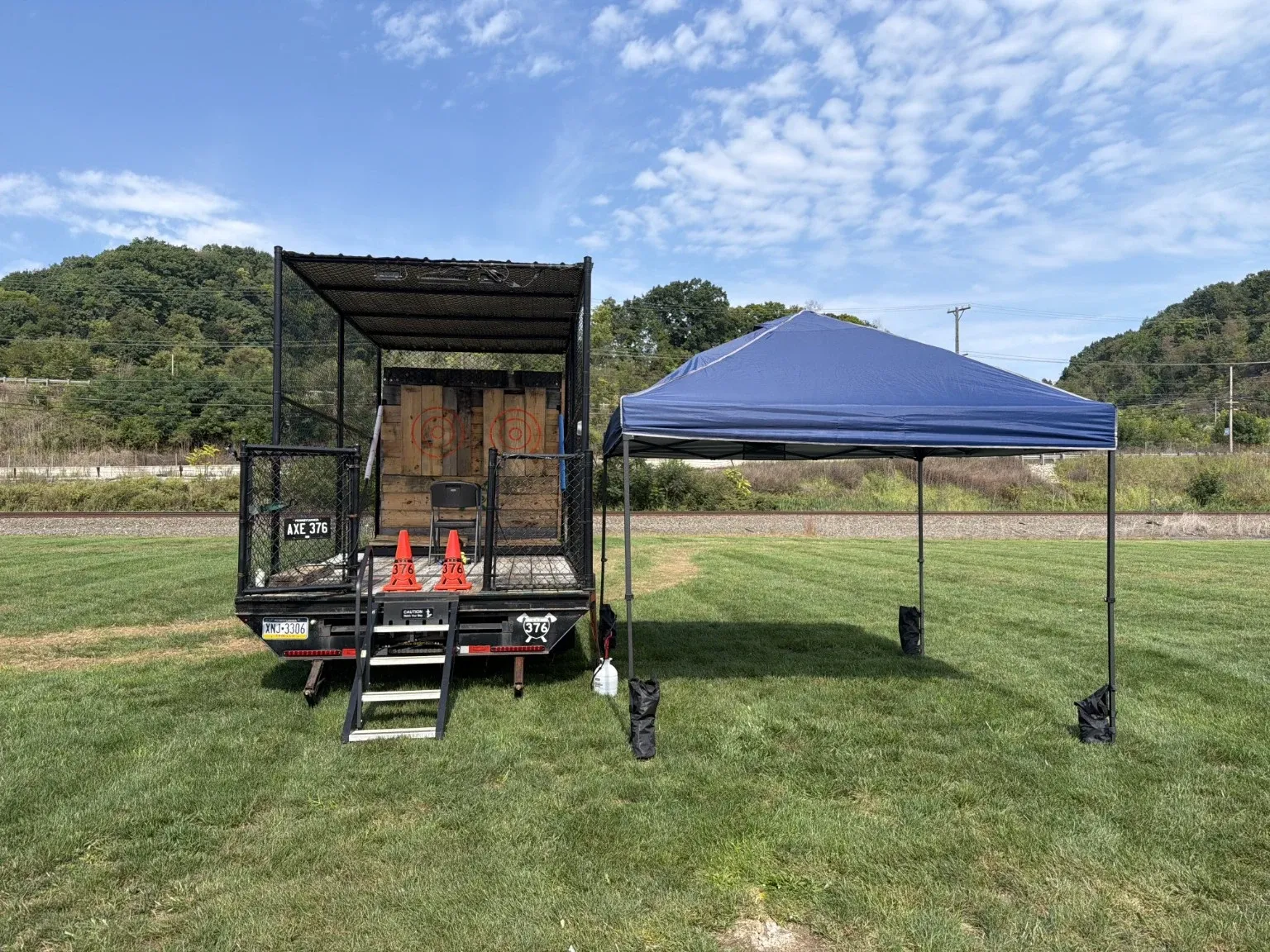 The AXE 376 black trailer and a canopy set up in a grassy field