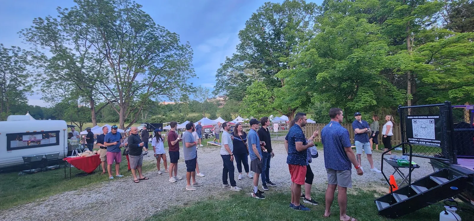 A crowd lined up at an outdoor community event with the axe trailer