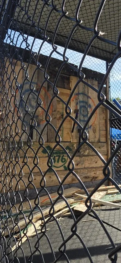 Close-up of a wooden target behind chain-link fencing